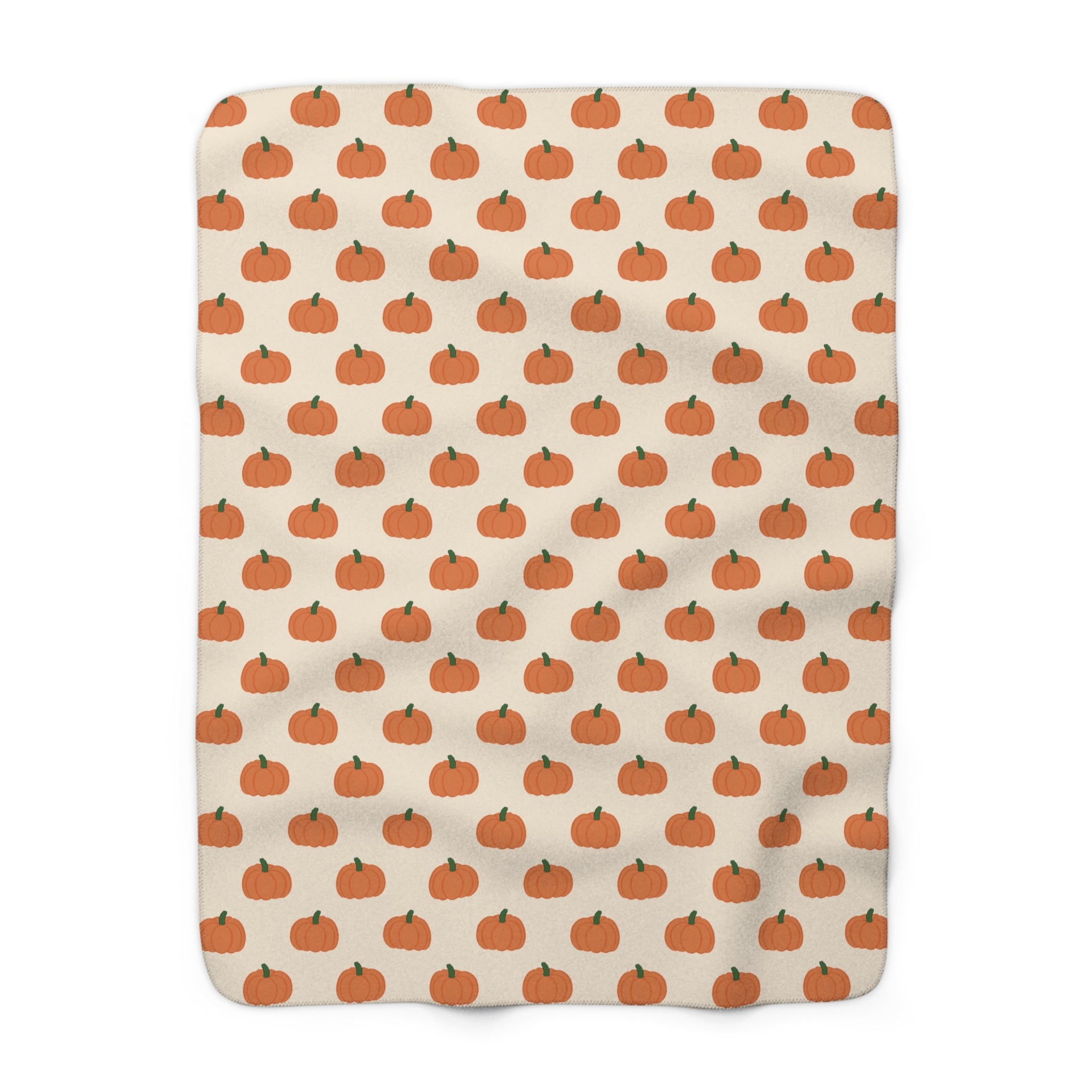 A rectangular blanket with a repeating pattern of small orange pumpkins on a warm cream background.