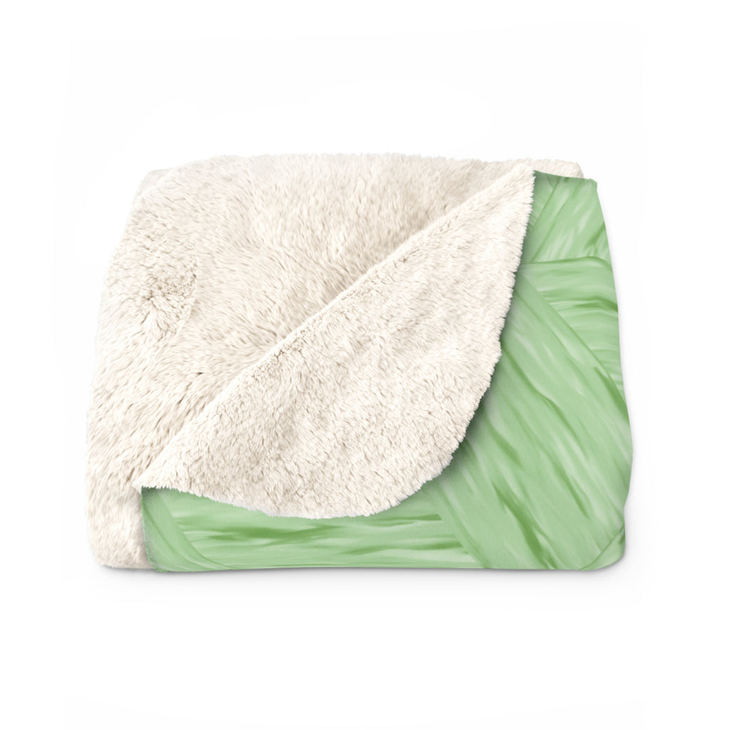 Folded blanket with white sherpa side and soft green pattern