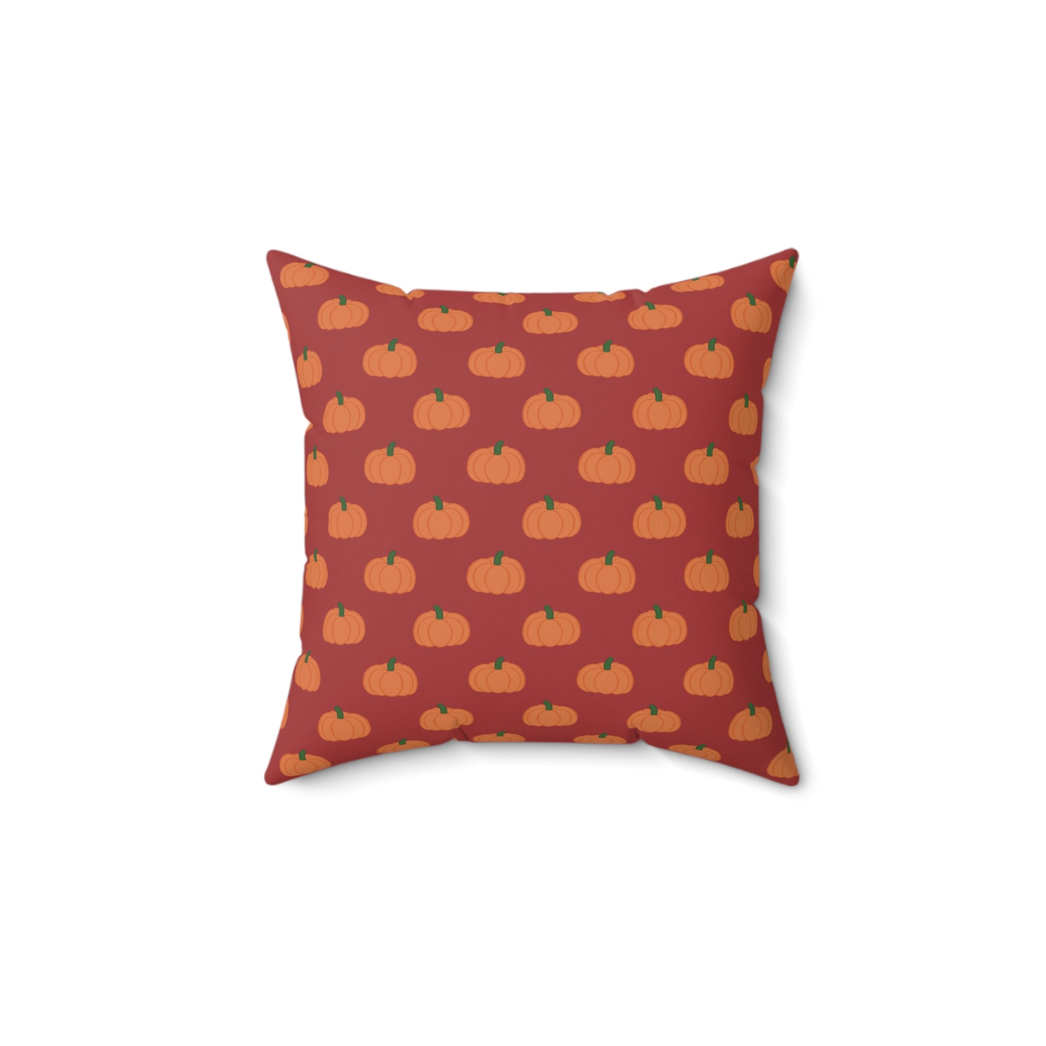 A square throw pillow featuring a repeating pattern of orange pumpkins with green stems on a muted red background.